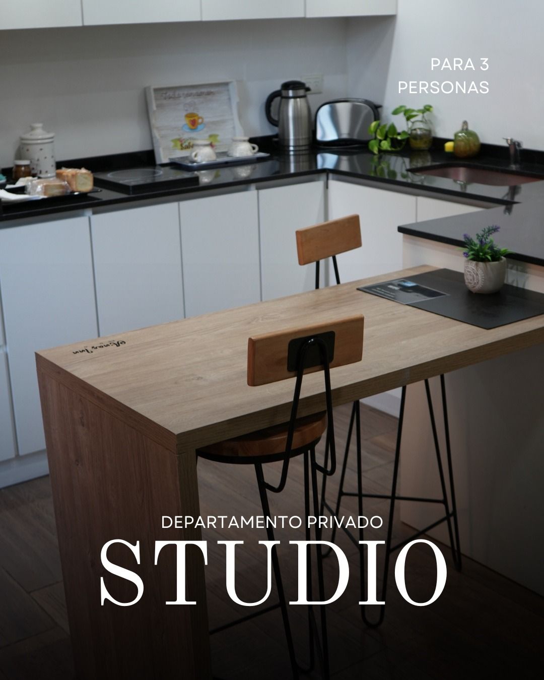 Apartamento tipo estudio con cocina con gabinetes blancos, barra de madera y encimera.