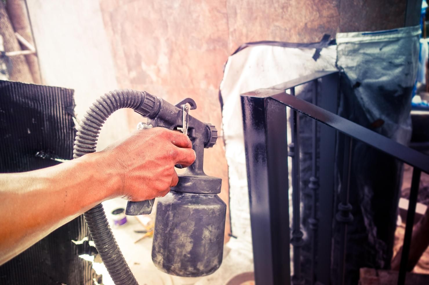 A Man Is Spraying Black Paint On A Piece Of Metal — Paint & Trade Supplies Lismore In Grafton, NSW
