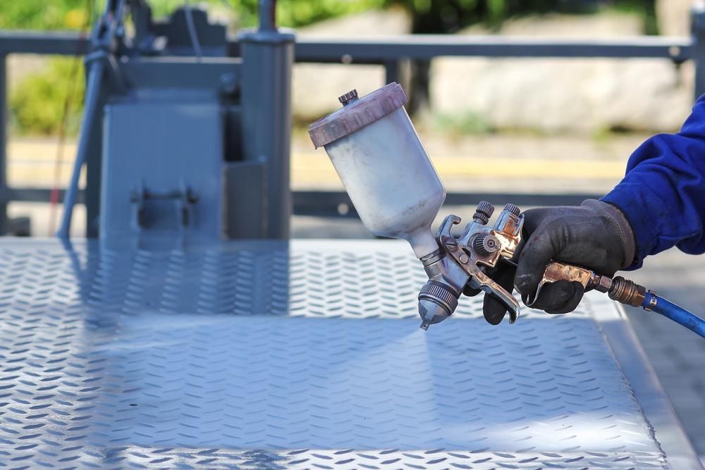 A Man Spraying A Paint On Metal Surface — Paint & Trade Supplies Lismore In Goonellabah, NSW
