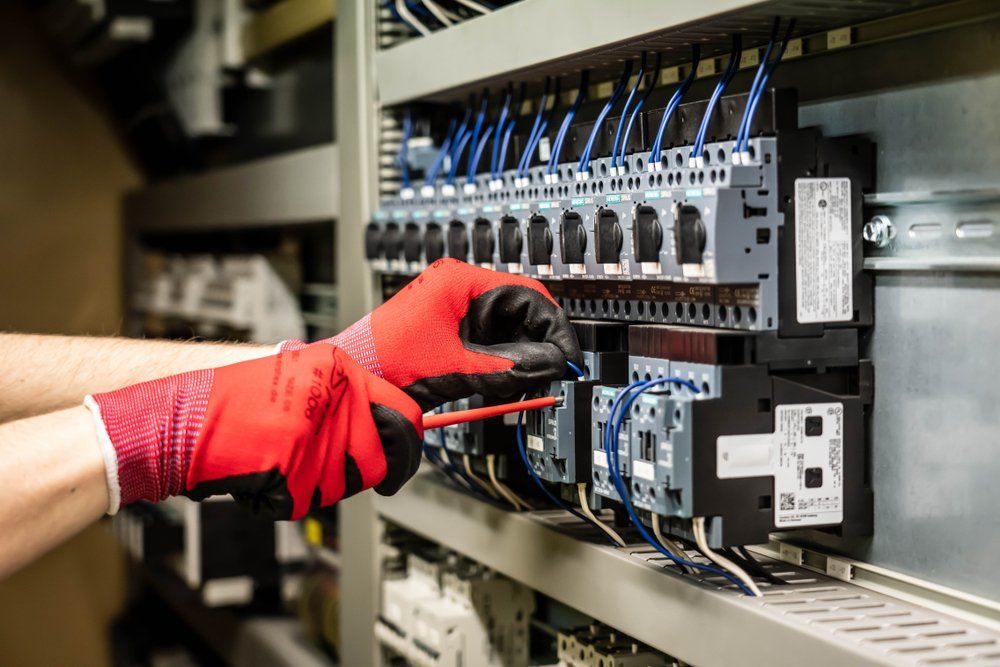 A Person Wearing Red Gloves is Working on an Electrical Panel — Hennig Electrical Services in Sunshine Coast, QLD
