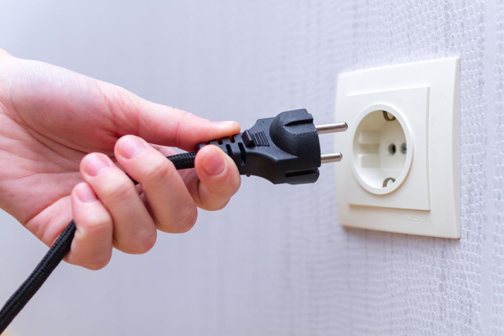A Person is Plugging a Plug Into an Electrical Outlet — Hennig Electrical Services in The Range, QLD
