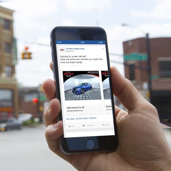 A person is holding a cell phone with a picture of a car on the screen