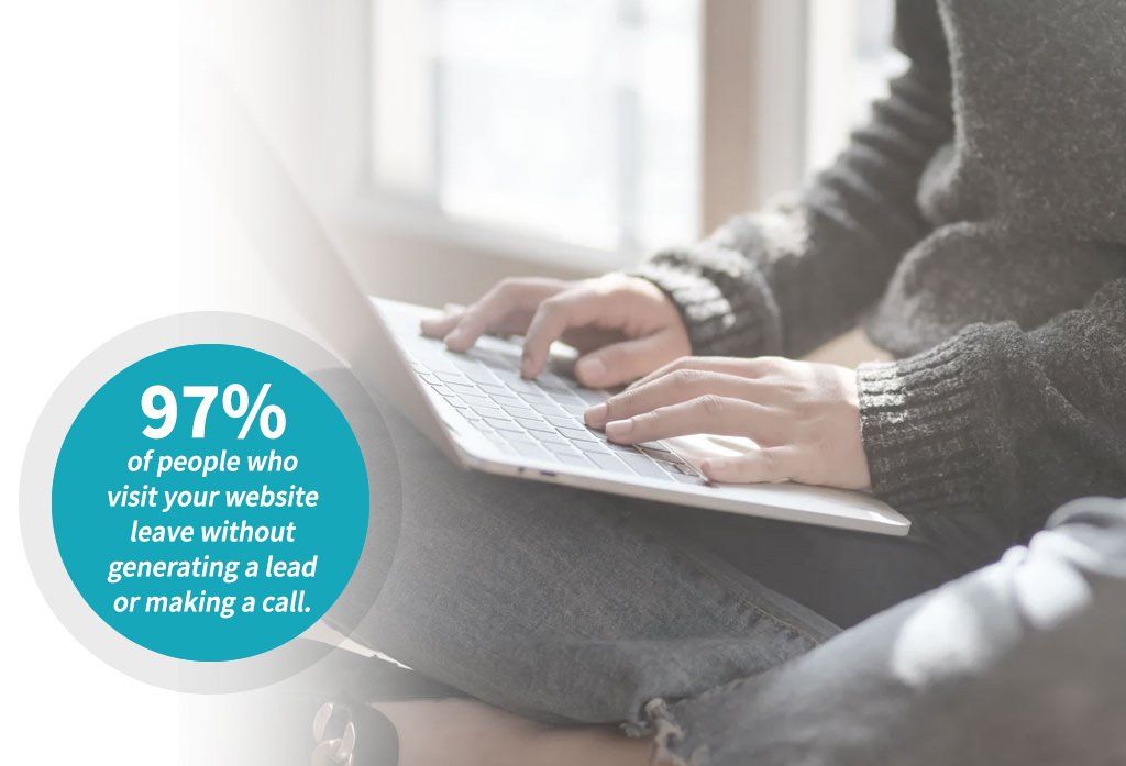 A person is typing on a laptop computer while sitting on the floor.