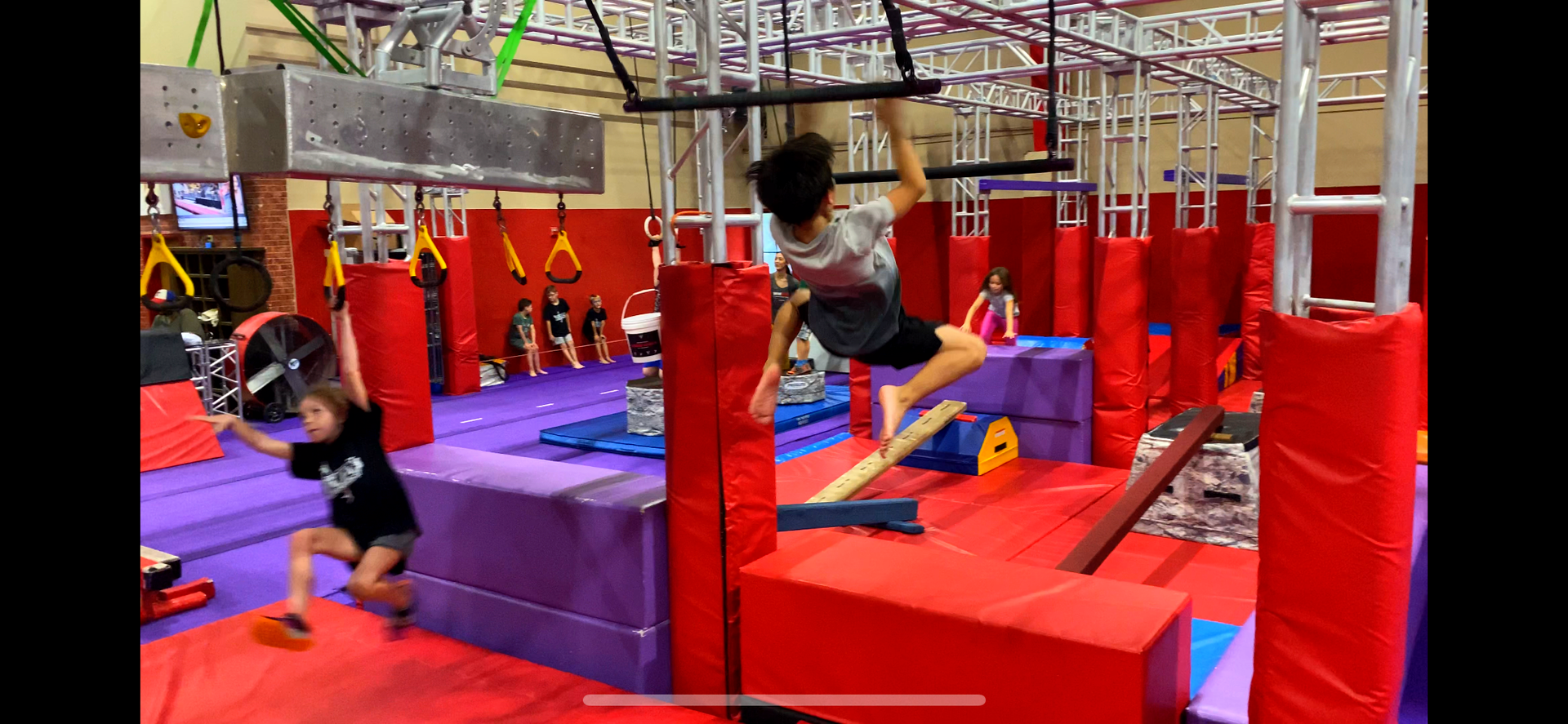 A group of children are playing in a ninja gym.