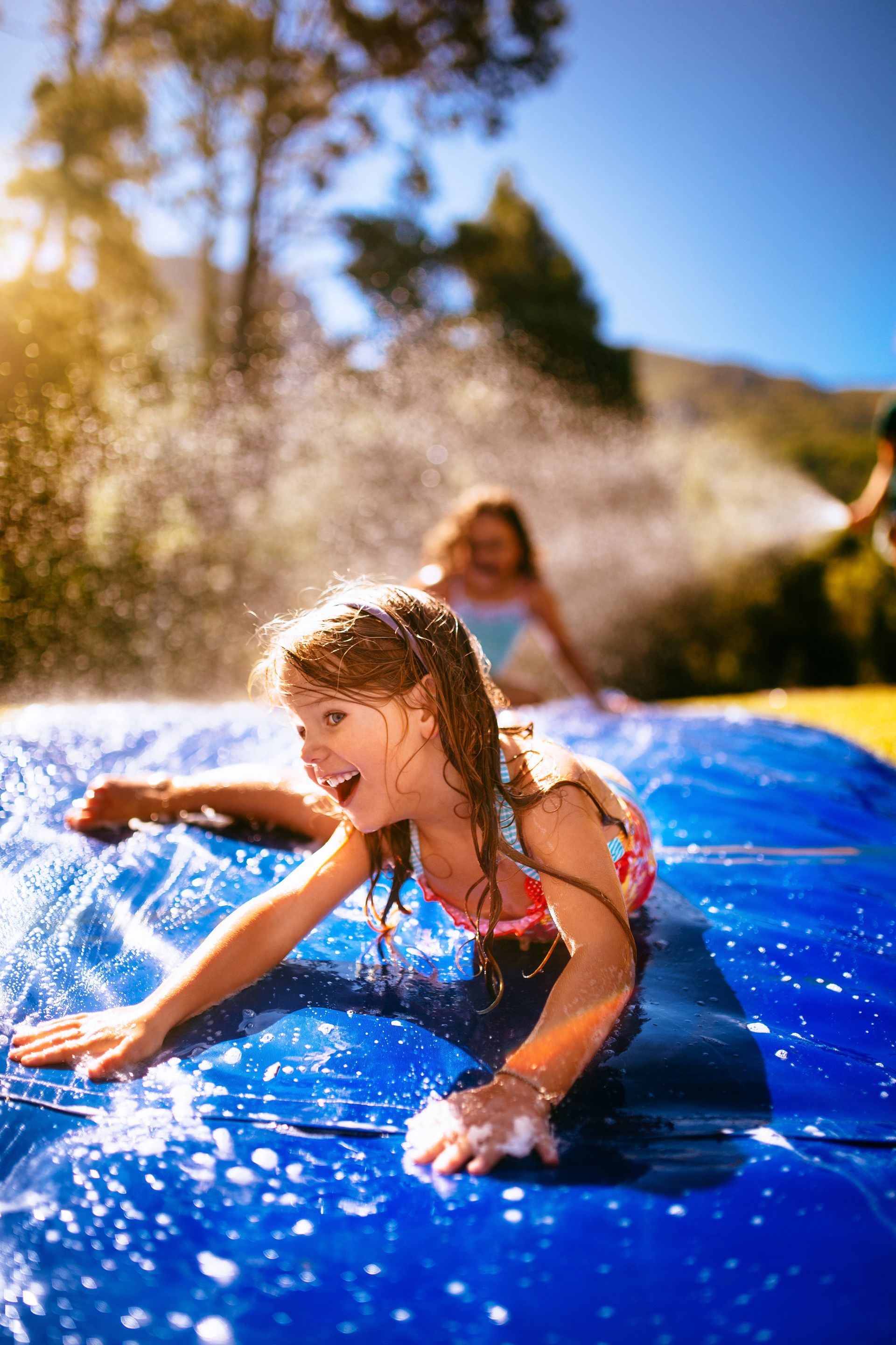 A little girl is playing on a water slide.