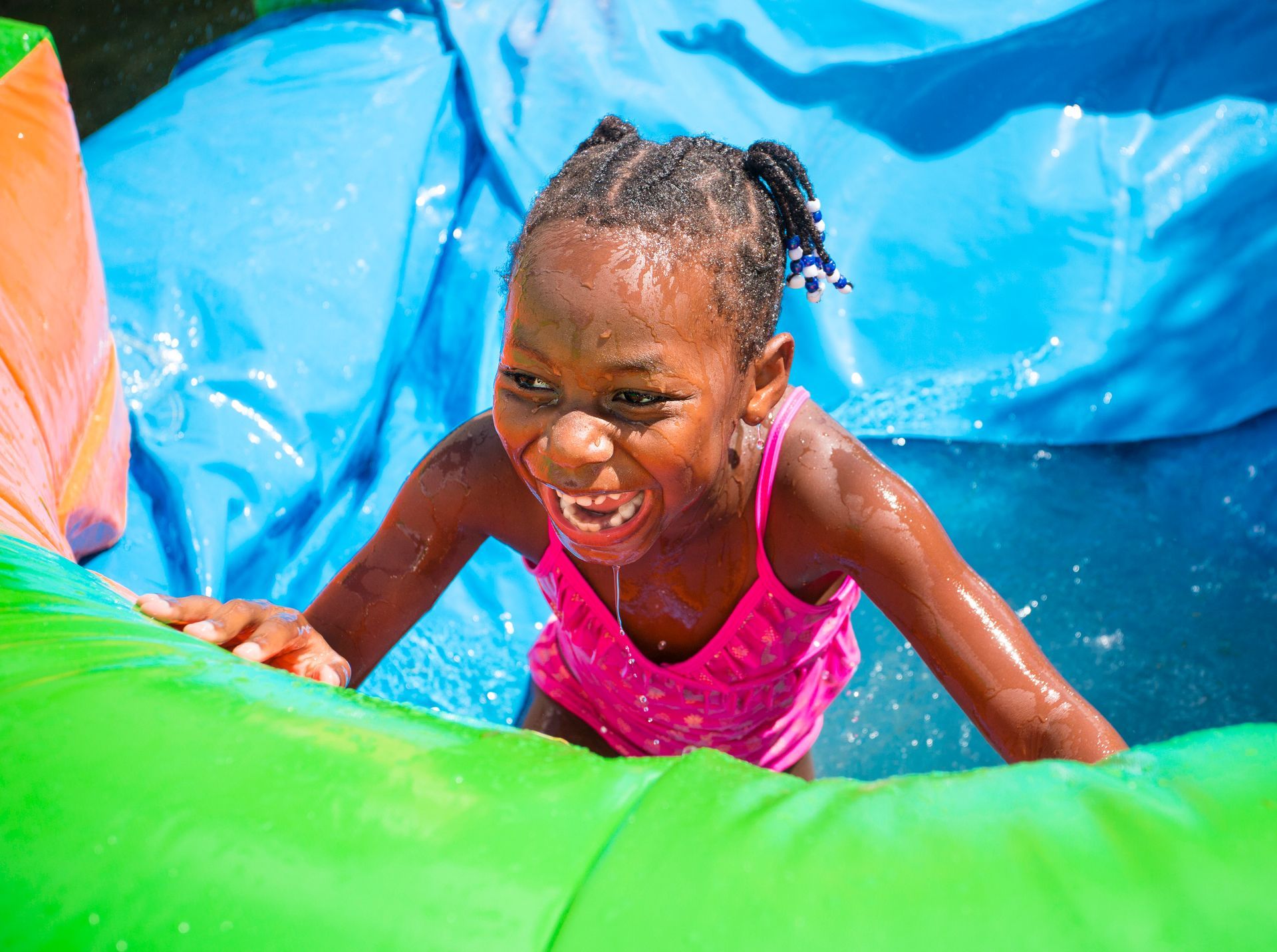 A little girl is playing in a water slide.