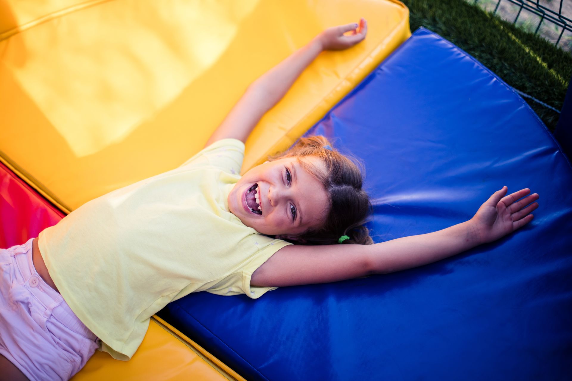 A young girl laying on a gymnastics mat whilst smiling