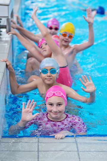 A group of children are swimming in a swimming pool.