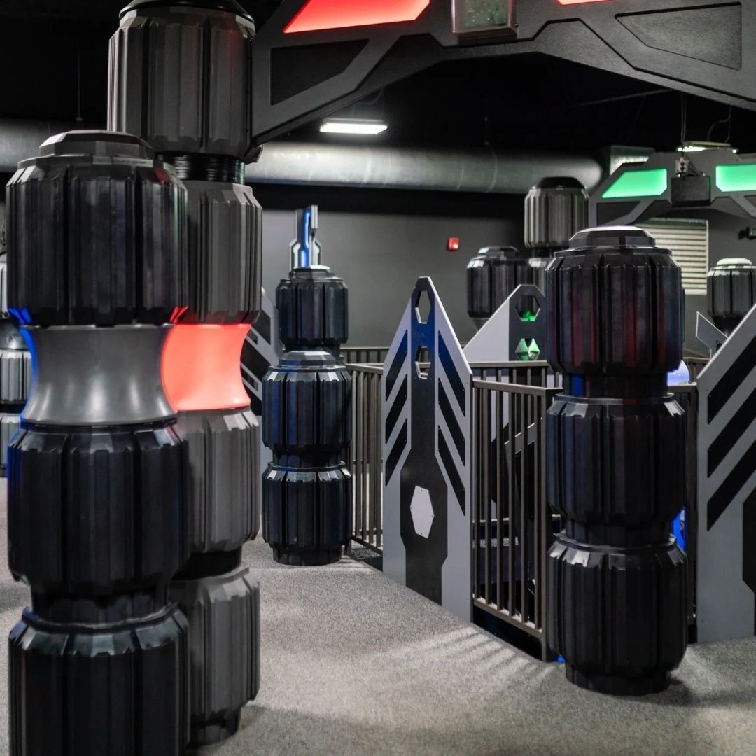 Laser tag arena with cylindrical black barriers and gray and blue walls.