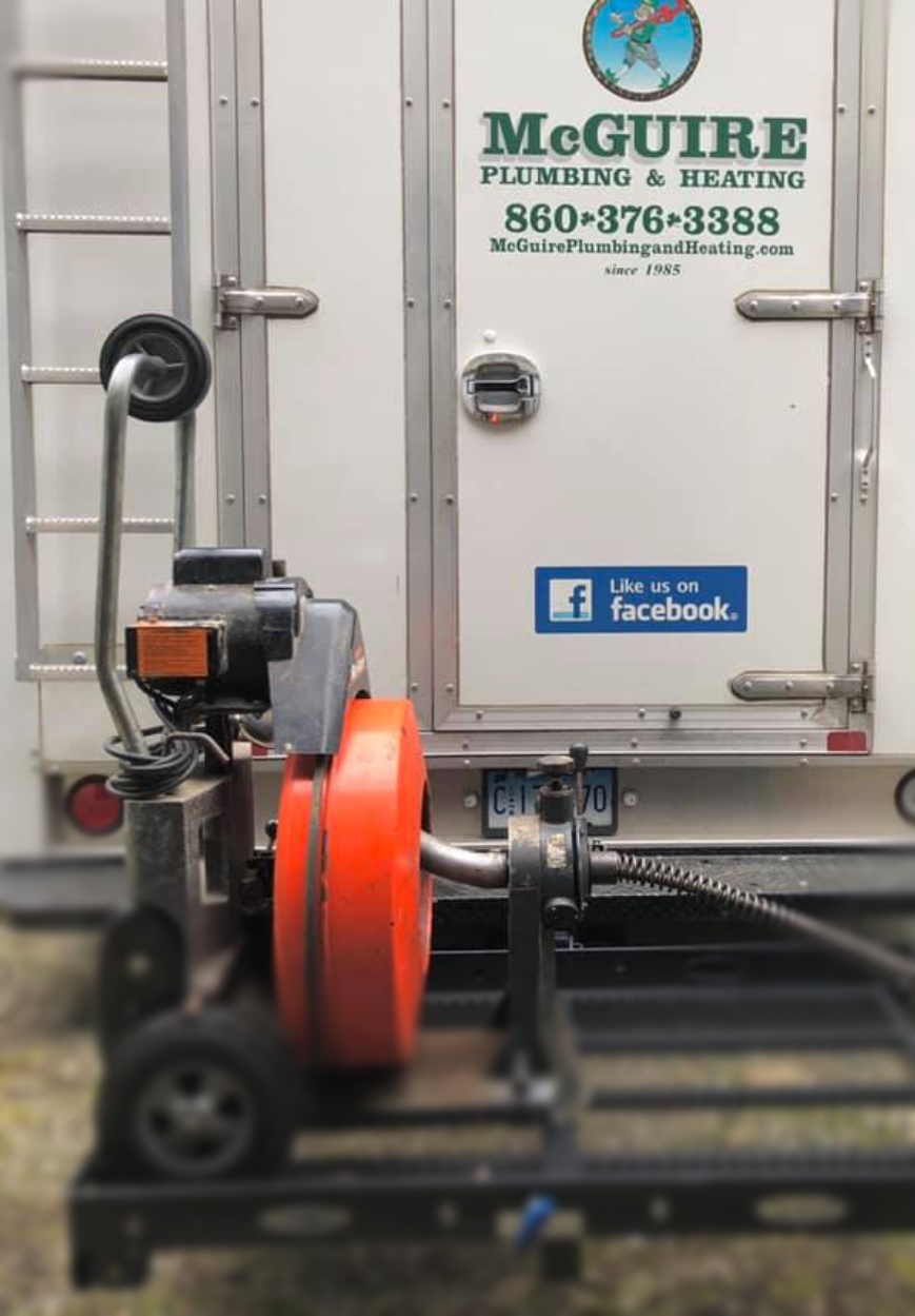 A mcguire plumbing and heating truck with a drain cleaner attached to it