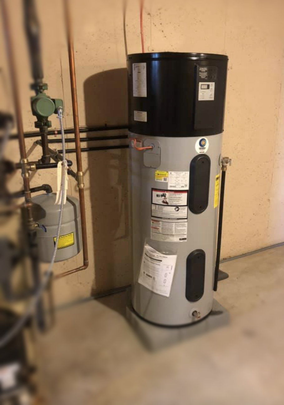 A water heater is sitting in a basement next to pipes.