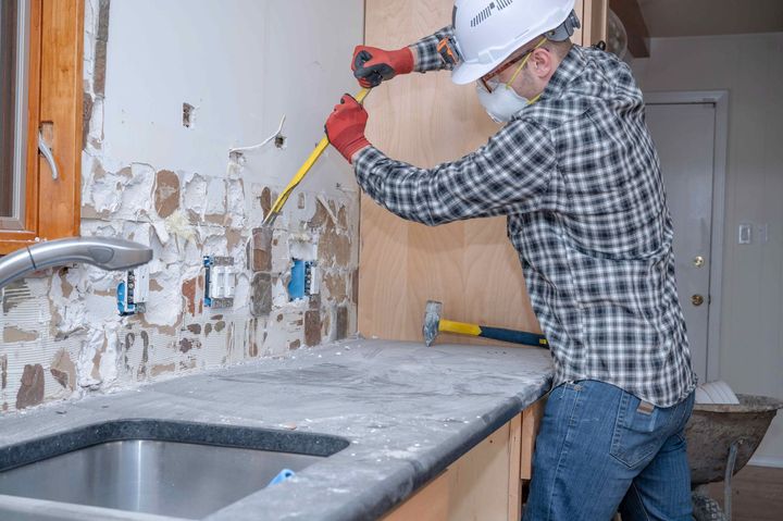 a man is working on a kitchen counter with a hammer and measuring tape