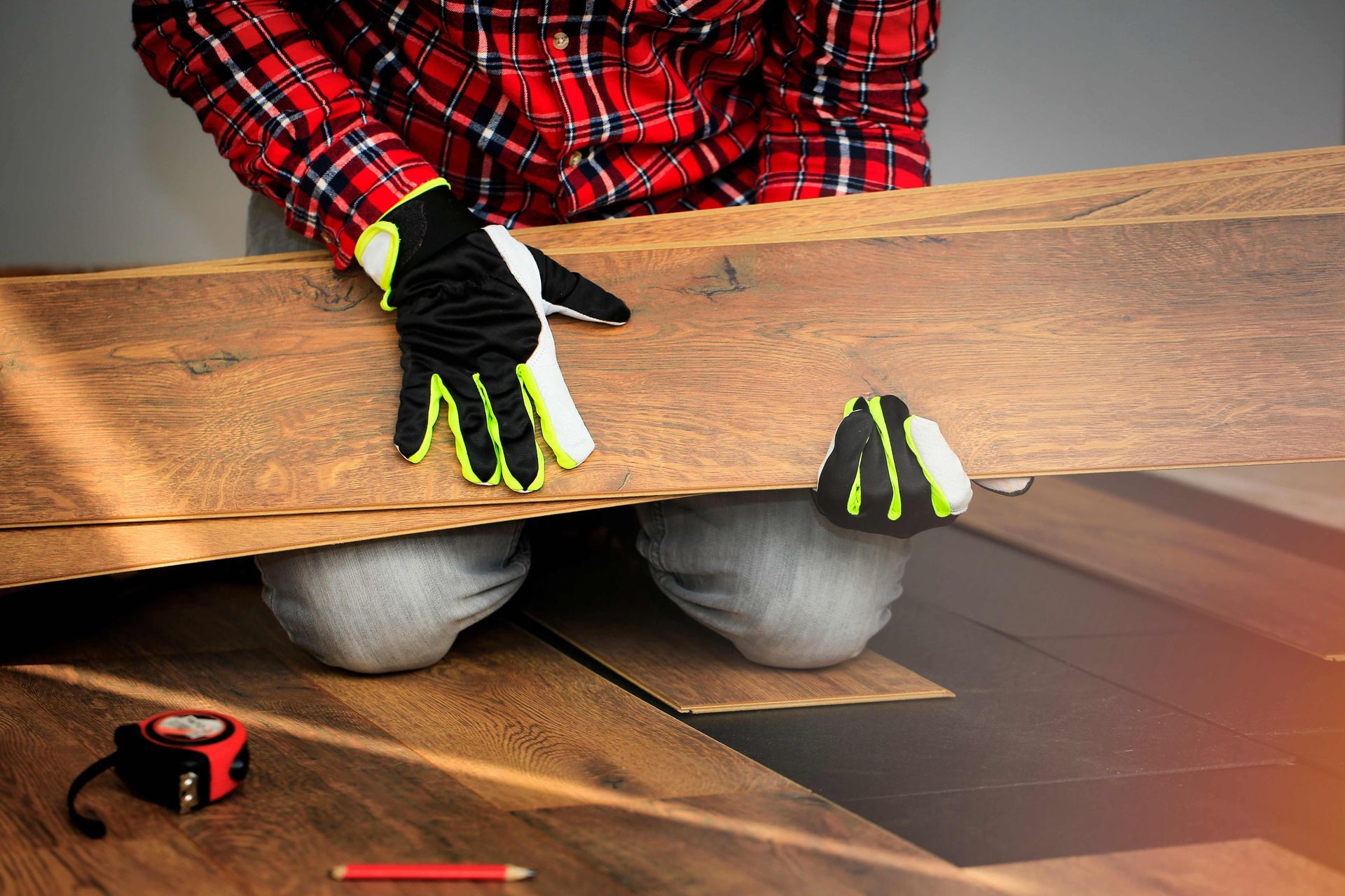 a man wearing gloves is installing a wooden floor