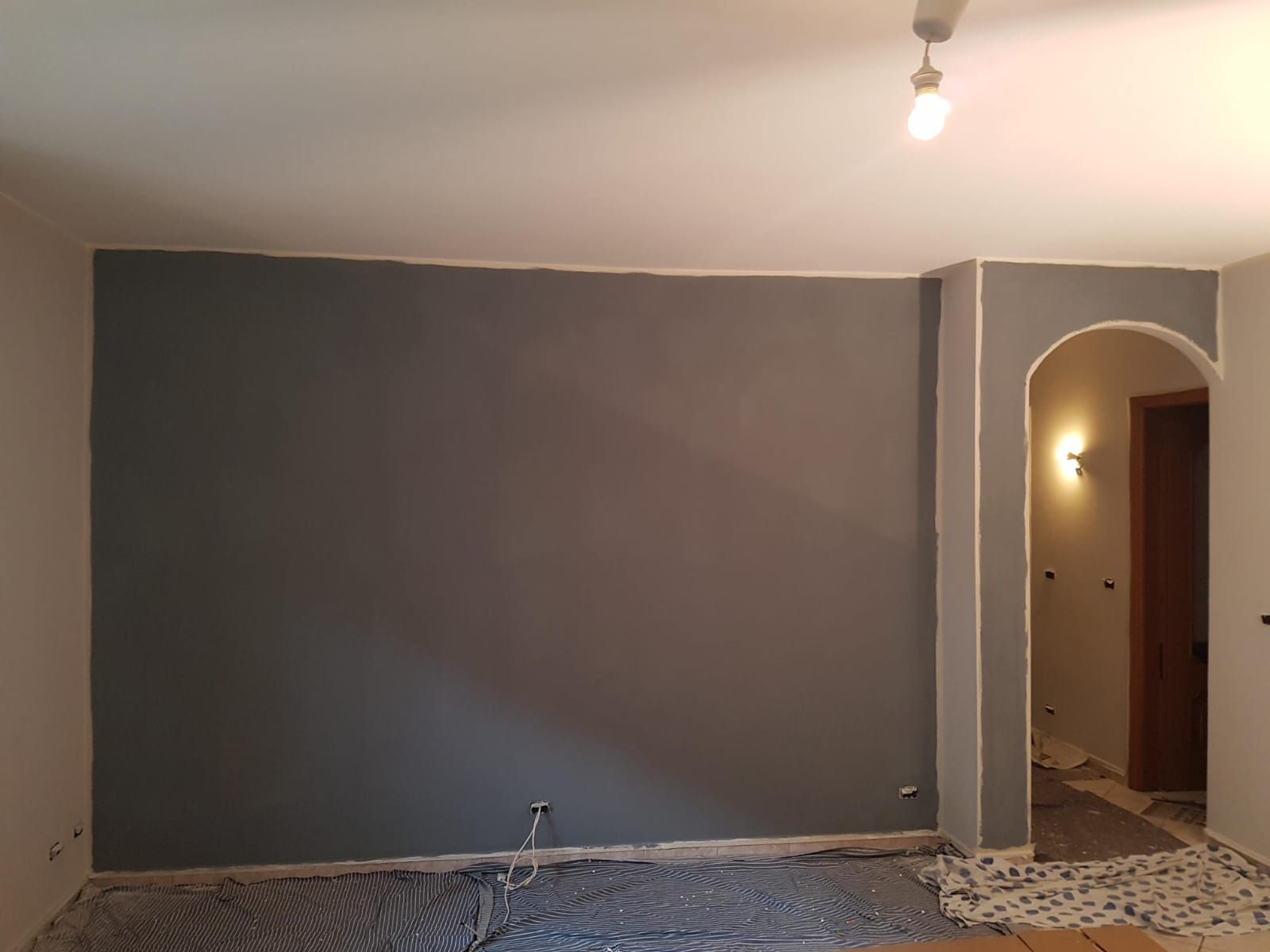 Un soggiorno con una parete grigia e una luce sul soffitto.