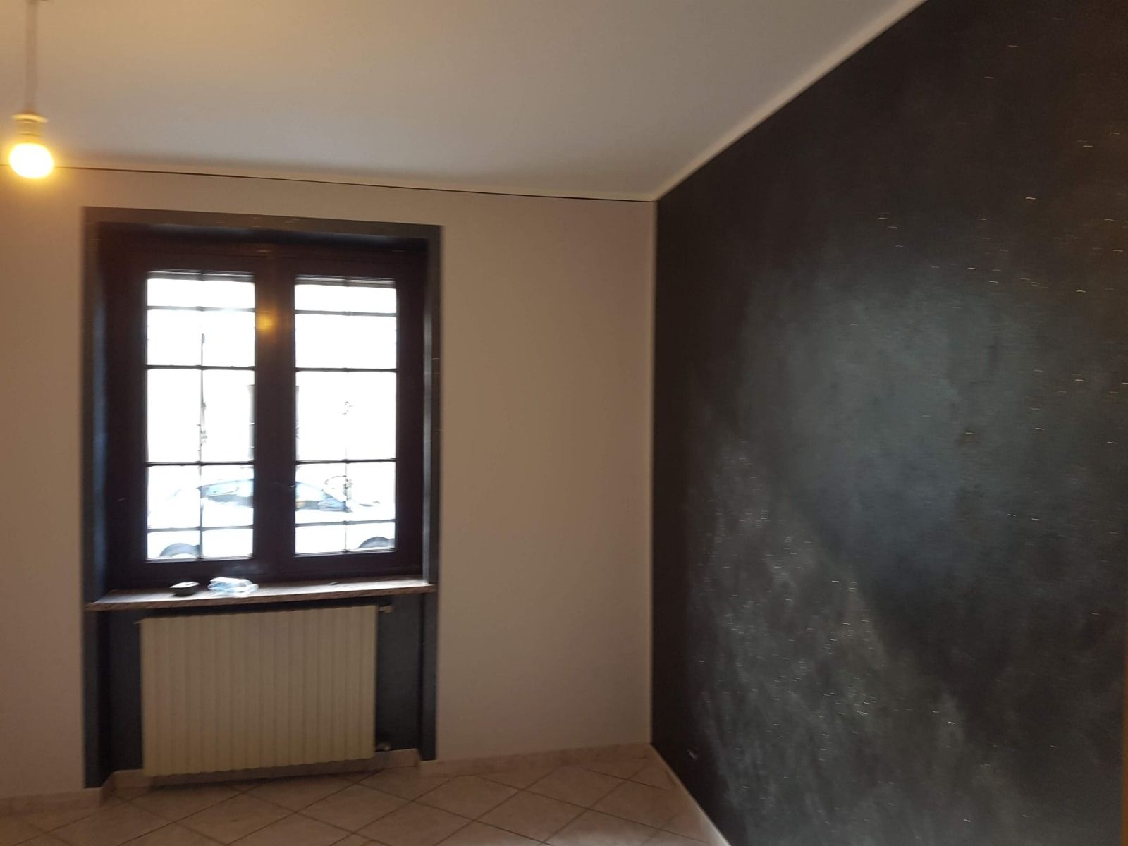 Una stanza vuota con un muro nero e una finestra