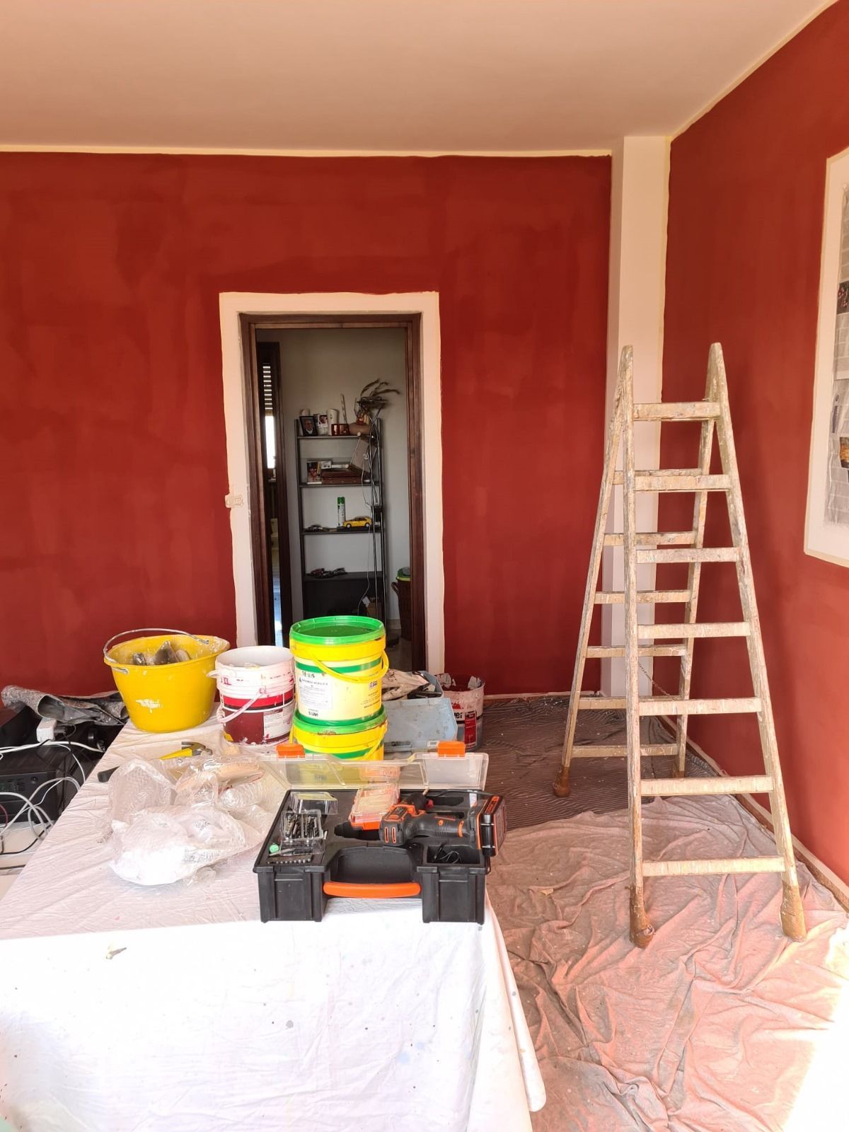 Una stanza viene dipinta con secchi di vernice e una scala.