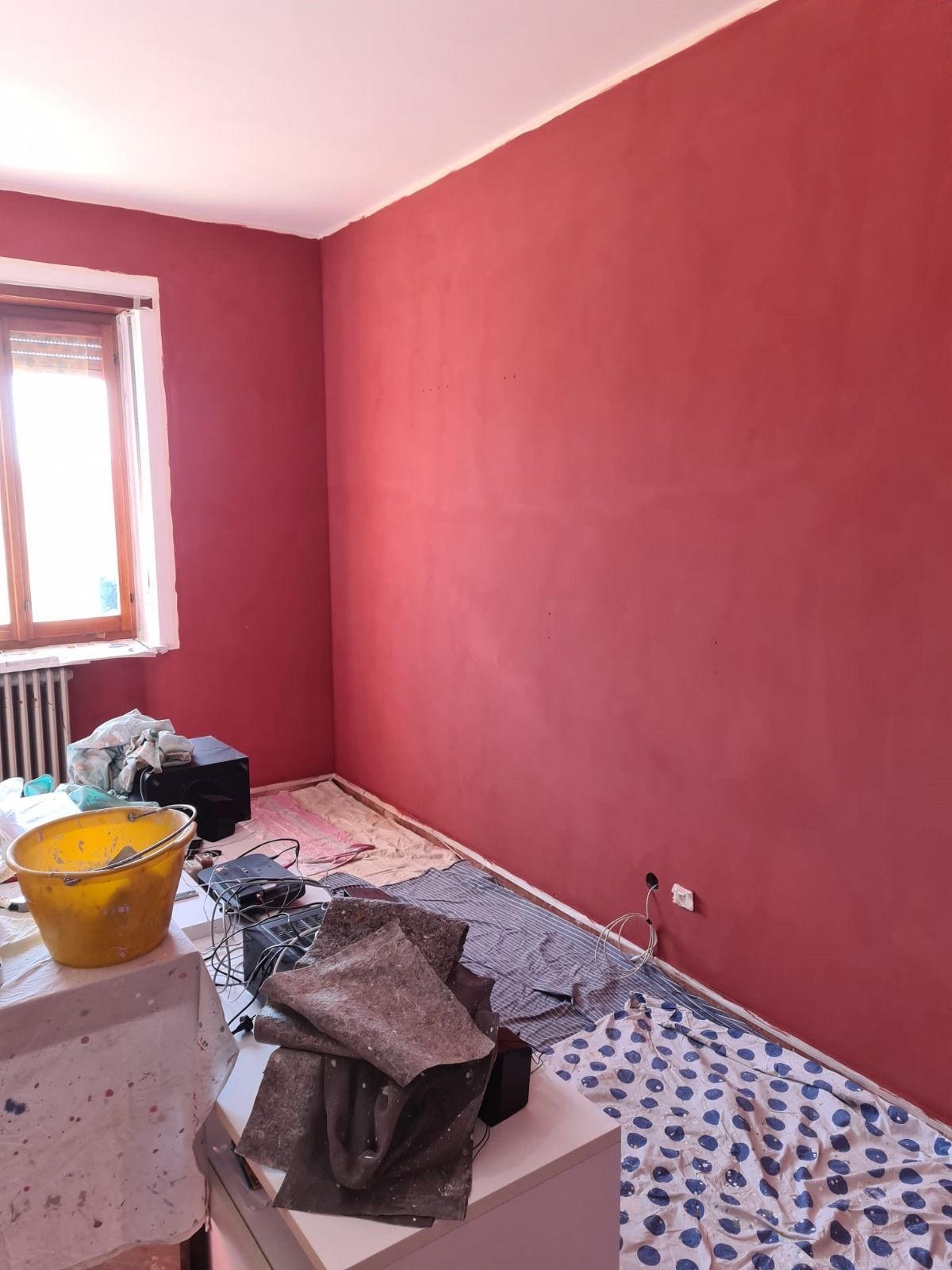 Una stanza con le pareti rosse e un secchio giallo sul pavimento.