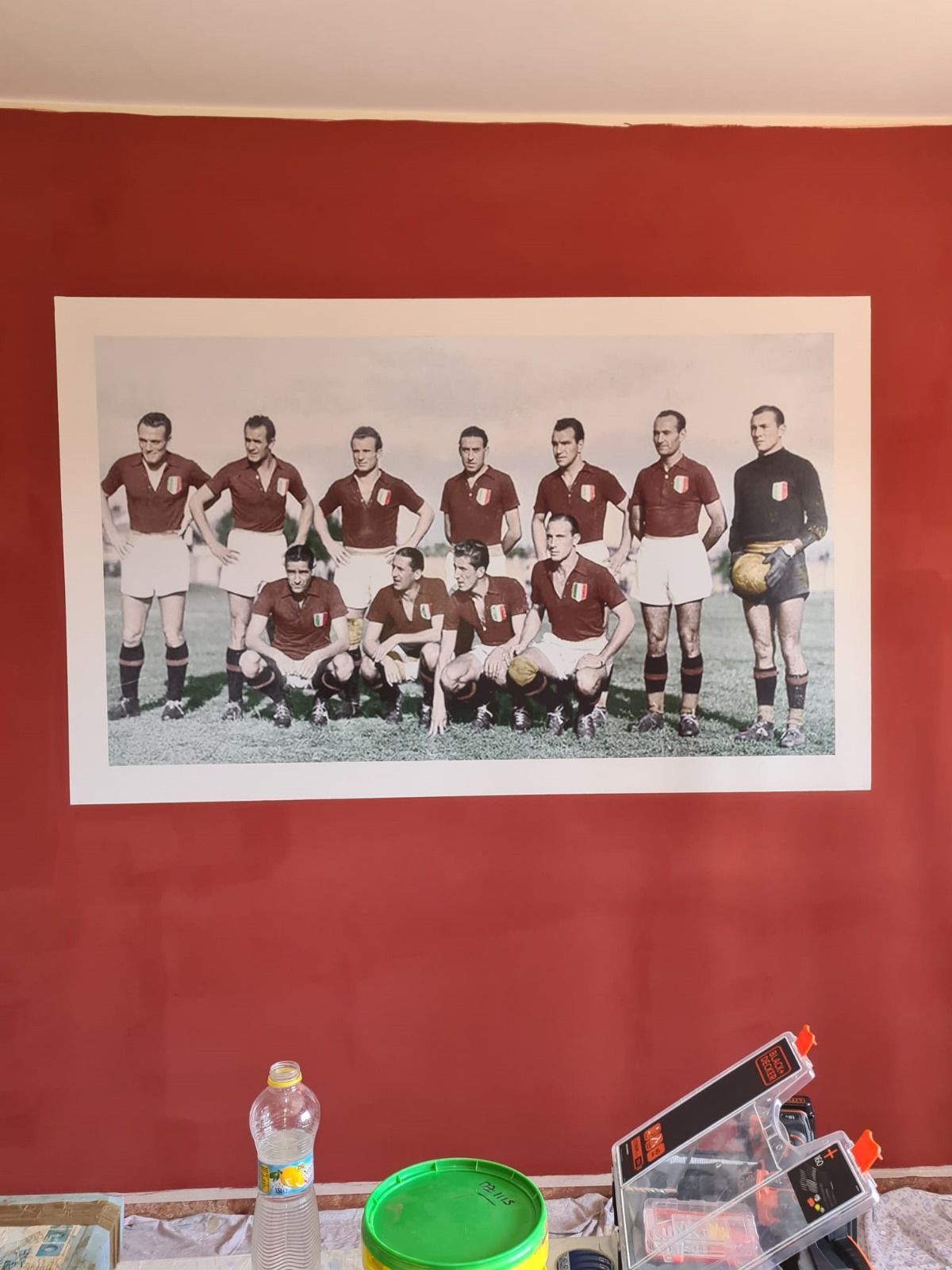 Su una parete rossa è appesa la foto di una squadra di calcio.