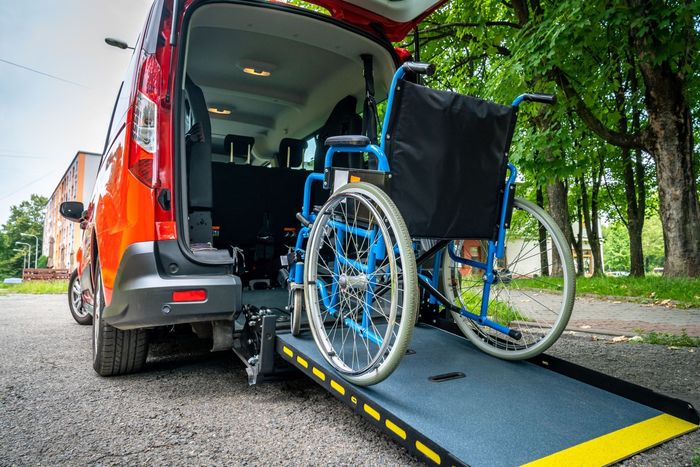 Red accessible van with a wheelchair on a ramp.