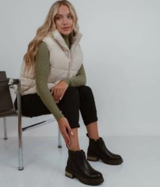 Mujer con botas negras con tachuelas, sentada, con las piernas cruzadas.