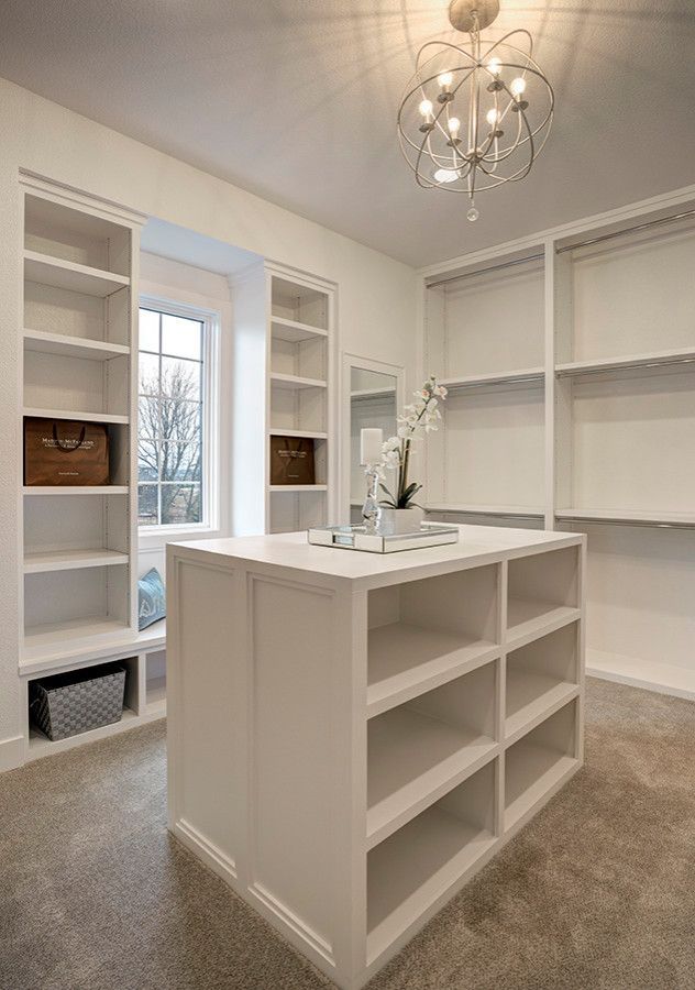 A walk in closet with lots of shelves and a large island in the middle