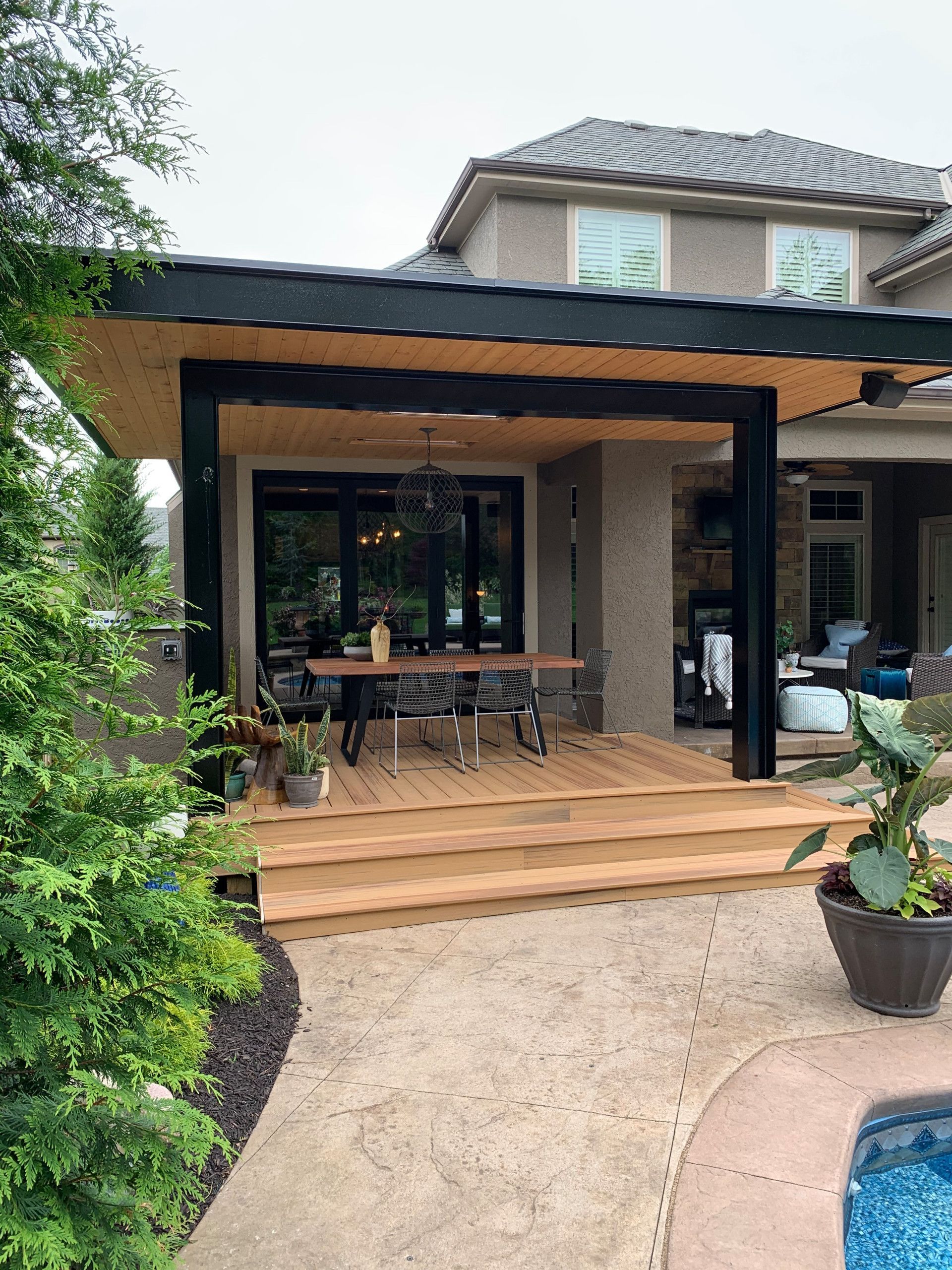 A wooden deck with a table and chairs under a covered patio next to a house