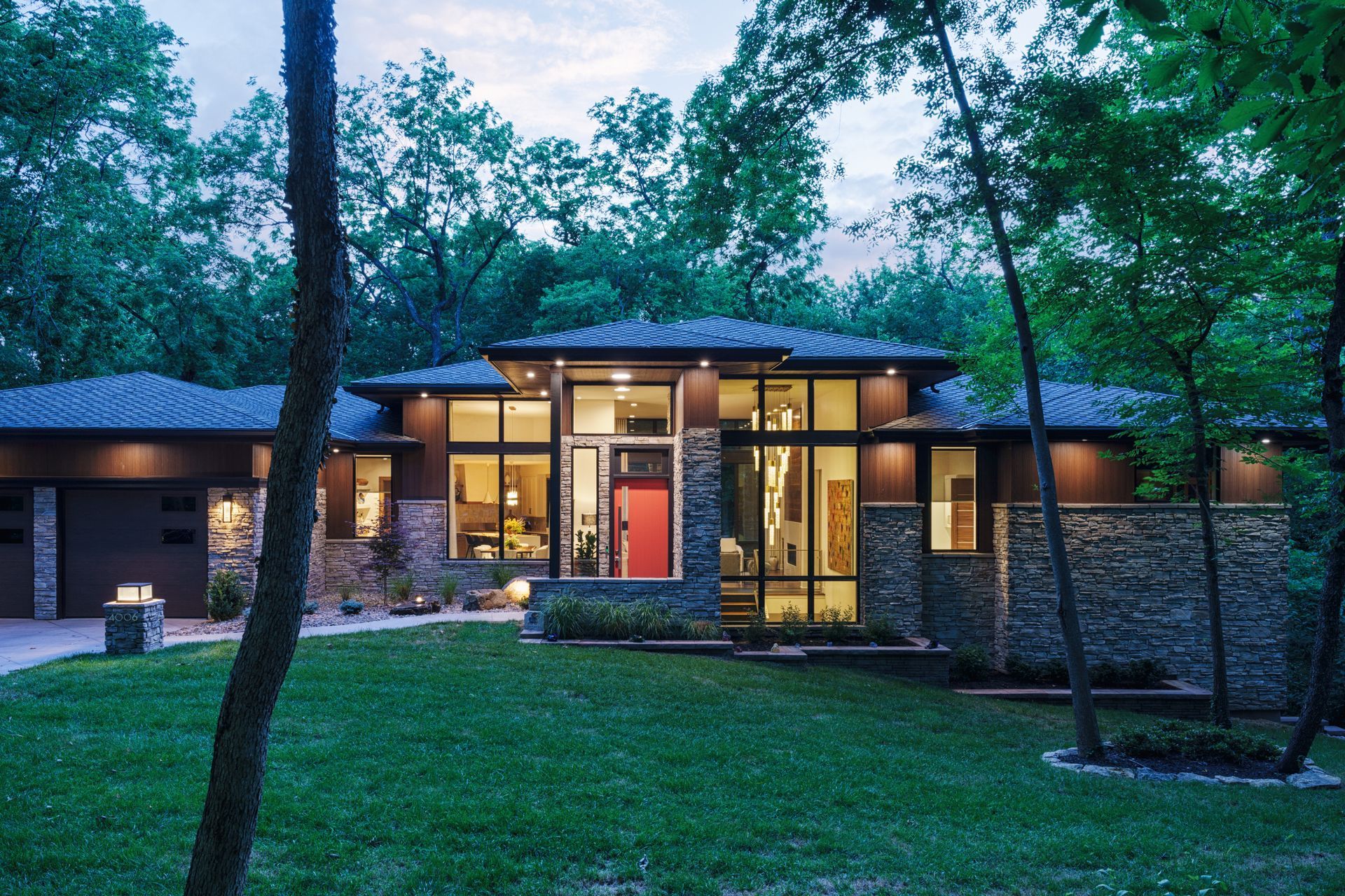 A modern house with a red door is surrounded by trees