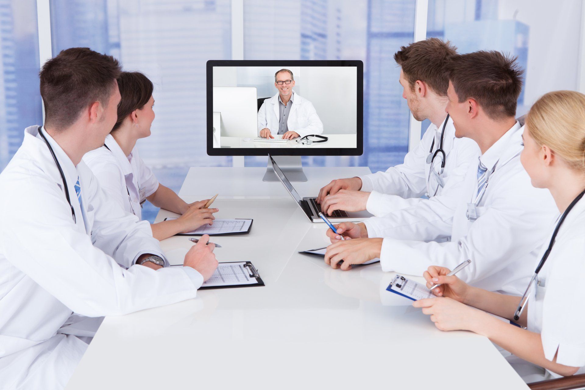 medical professionals sitting at table having a virtual meeting