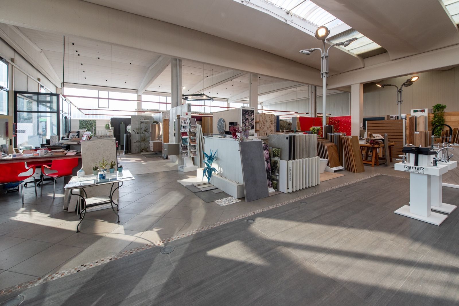 Ampio showroom con campioni di piastrelle, legno e altri materiali da costruzione. Luminoso, con luce e stand espositivi.