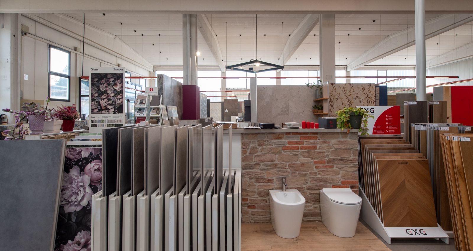 Interno dello showroom di piastrelle con campioni di piastrelle, sanitari e scaffali espositivi.