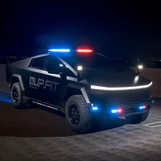 A black police car is parked in a parking lot at night.