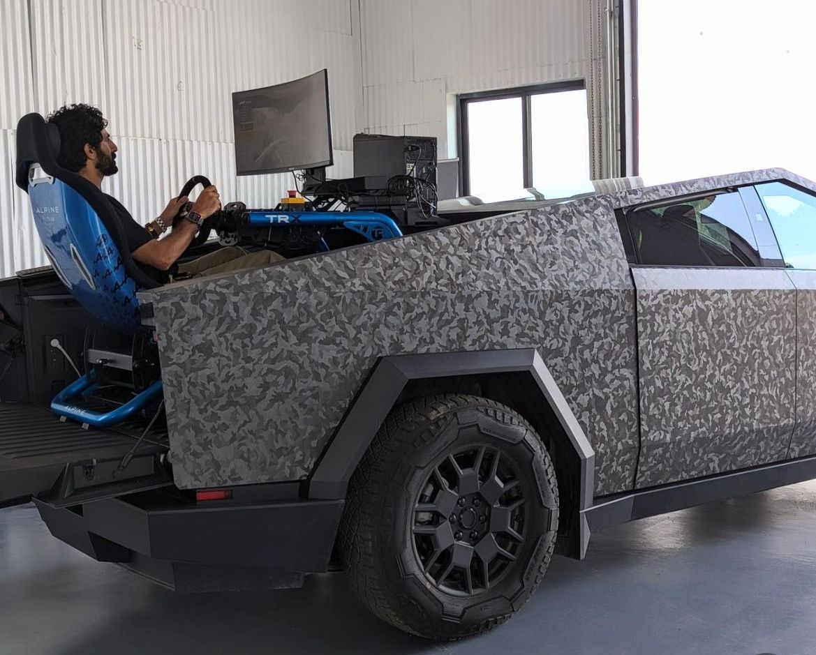 A man is sitting in a car with a computer on the back.