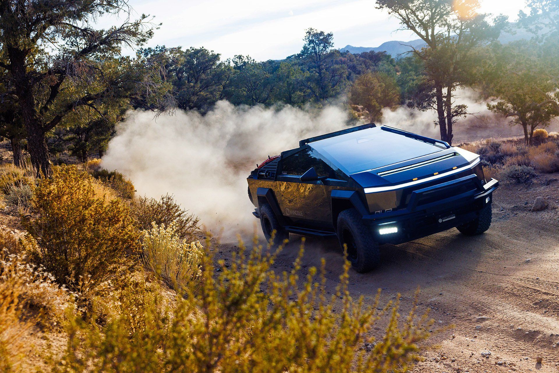 A black suv is driving down a dirt road in the desert.