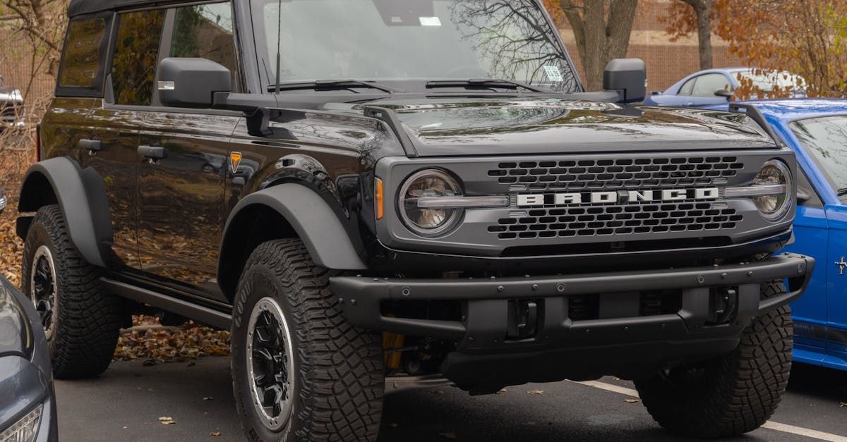 A black ford bronco is parked in a parking lot next to a blue jeep.