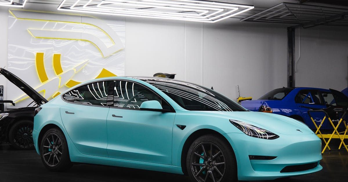 A blue tesla model 3 is parked in a garage.