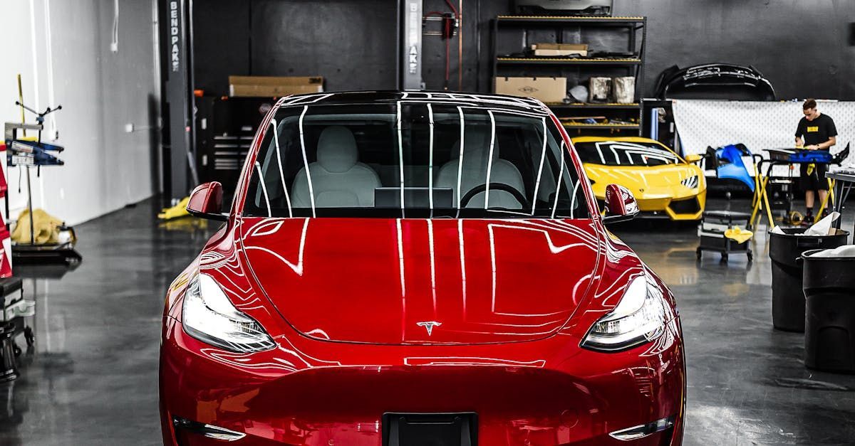 A red tesla model 3 is parked in a garage.