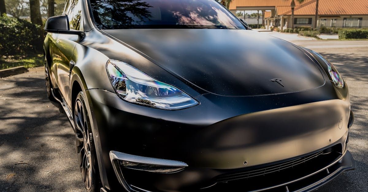 A black tesla model 3 is parked on the side of the road.