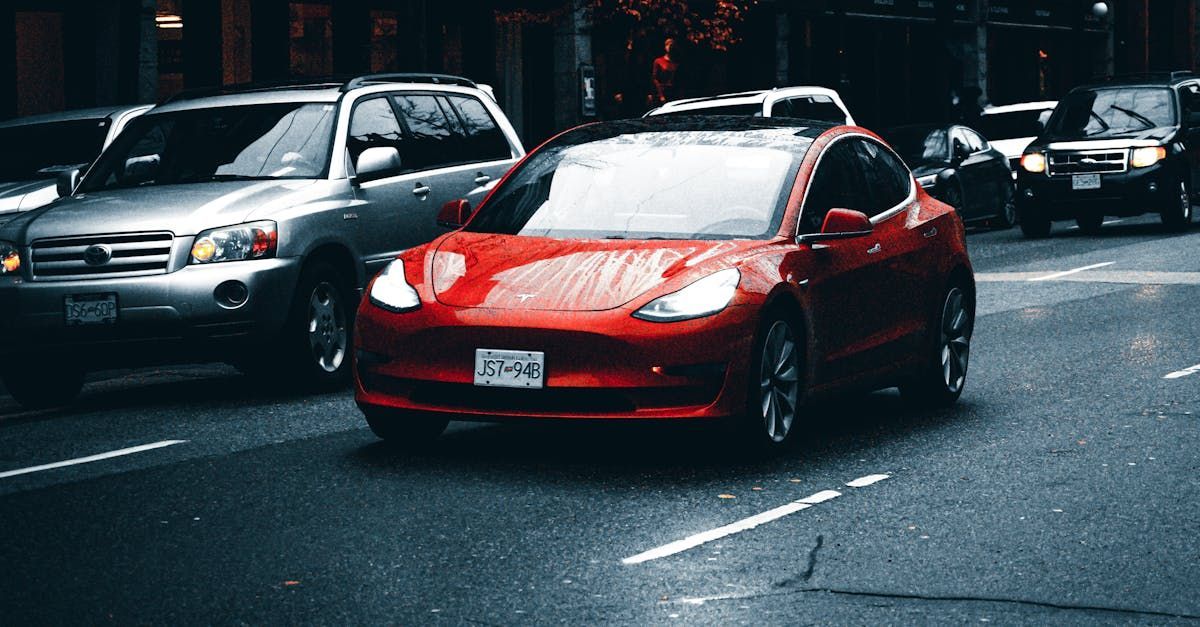 A red tesla model 3 is driving down a city street.