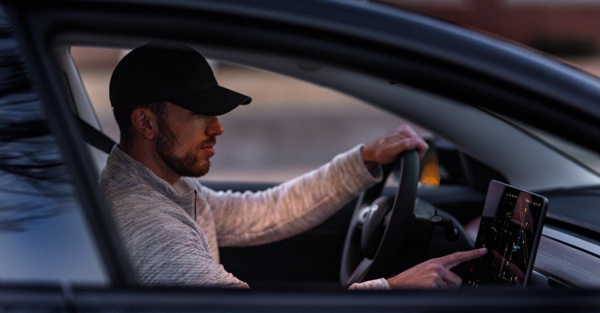 A man is driving a car and using a tablet.