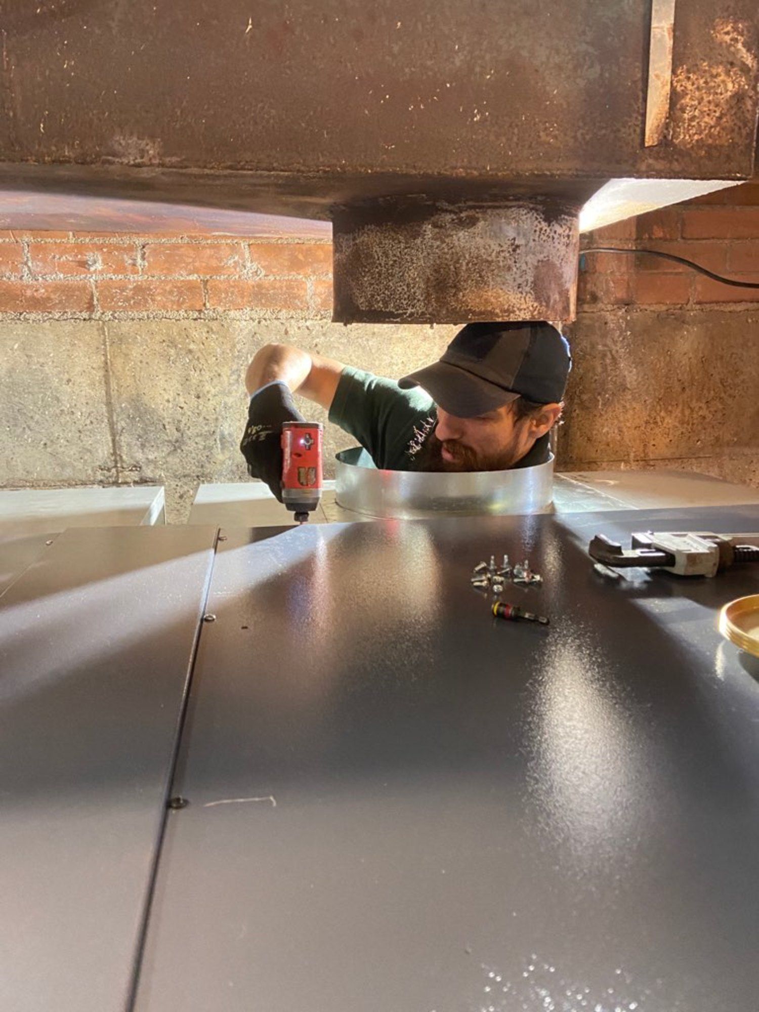 A man is working on a piece of metal in a basement.