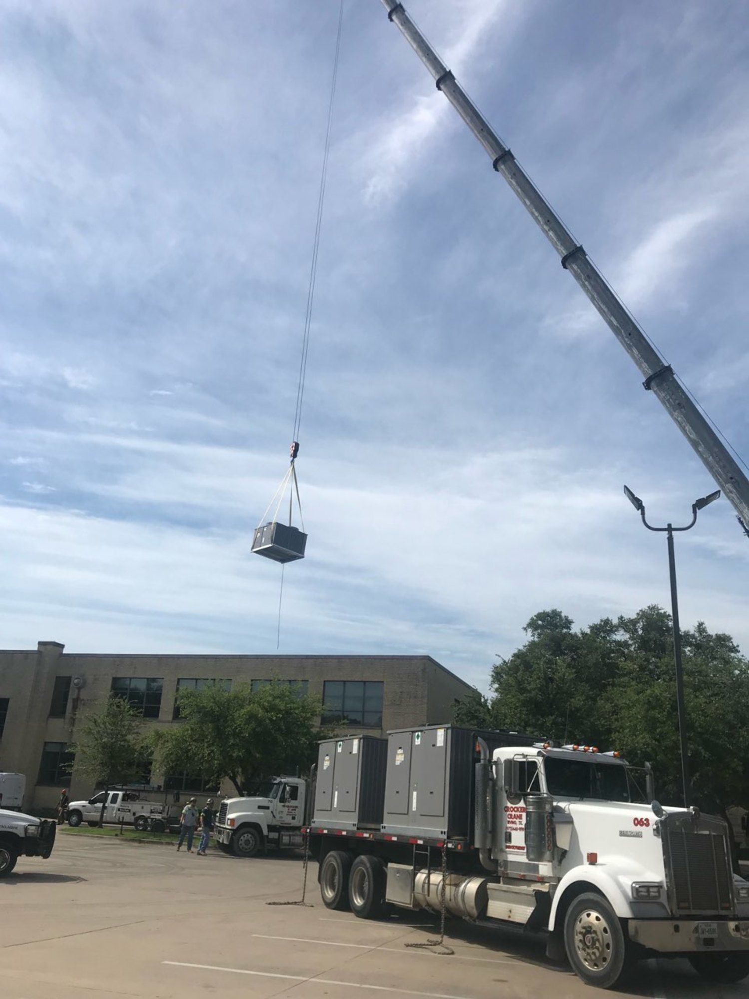 A truck is being lifted by a crane in a parking lot