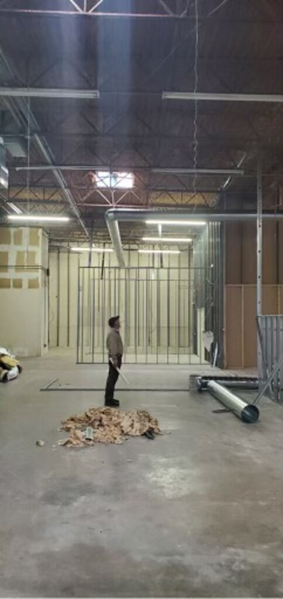 A man is standing in a large empty warehouse.