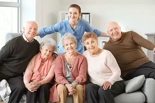 A group of elderly people are sitting on a couch with a nurse.