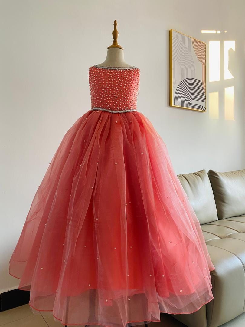 A pink flower girl dress is on a mannequin in a living room.