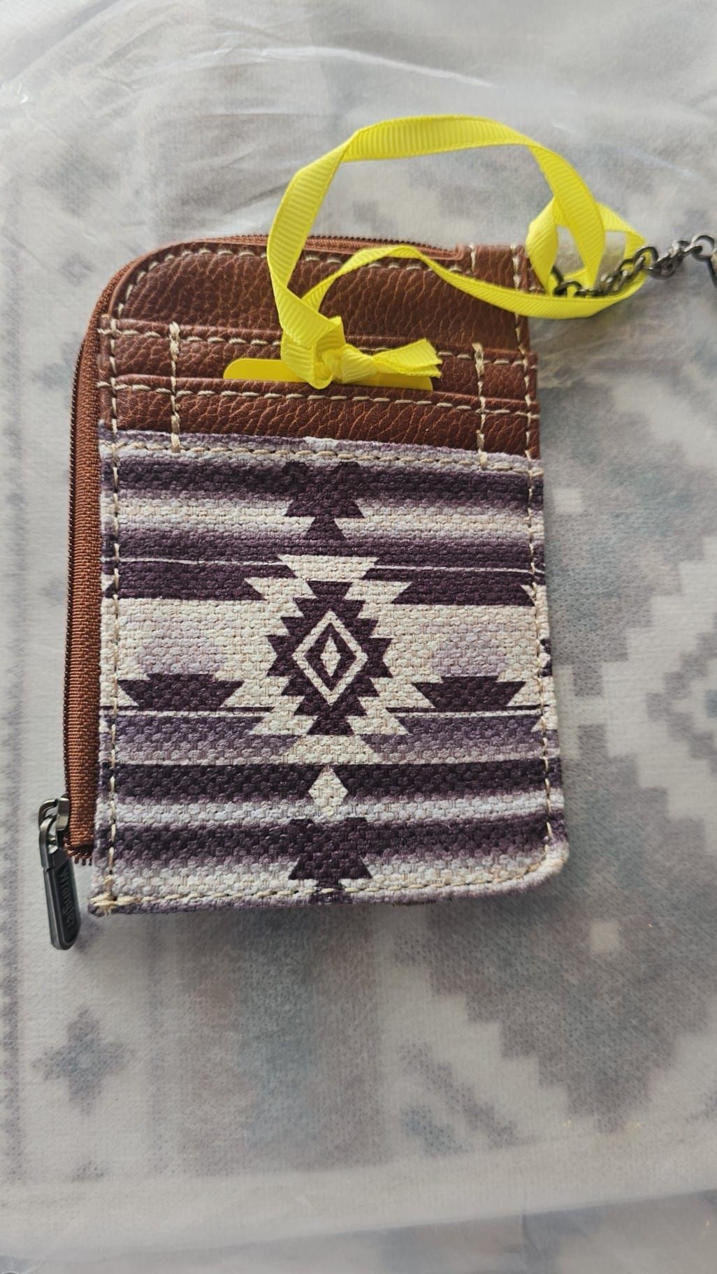 A small wallet with a yellow strap is sitting on a table.