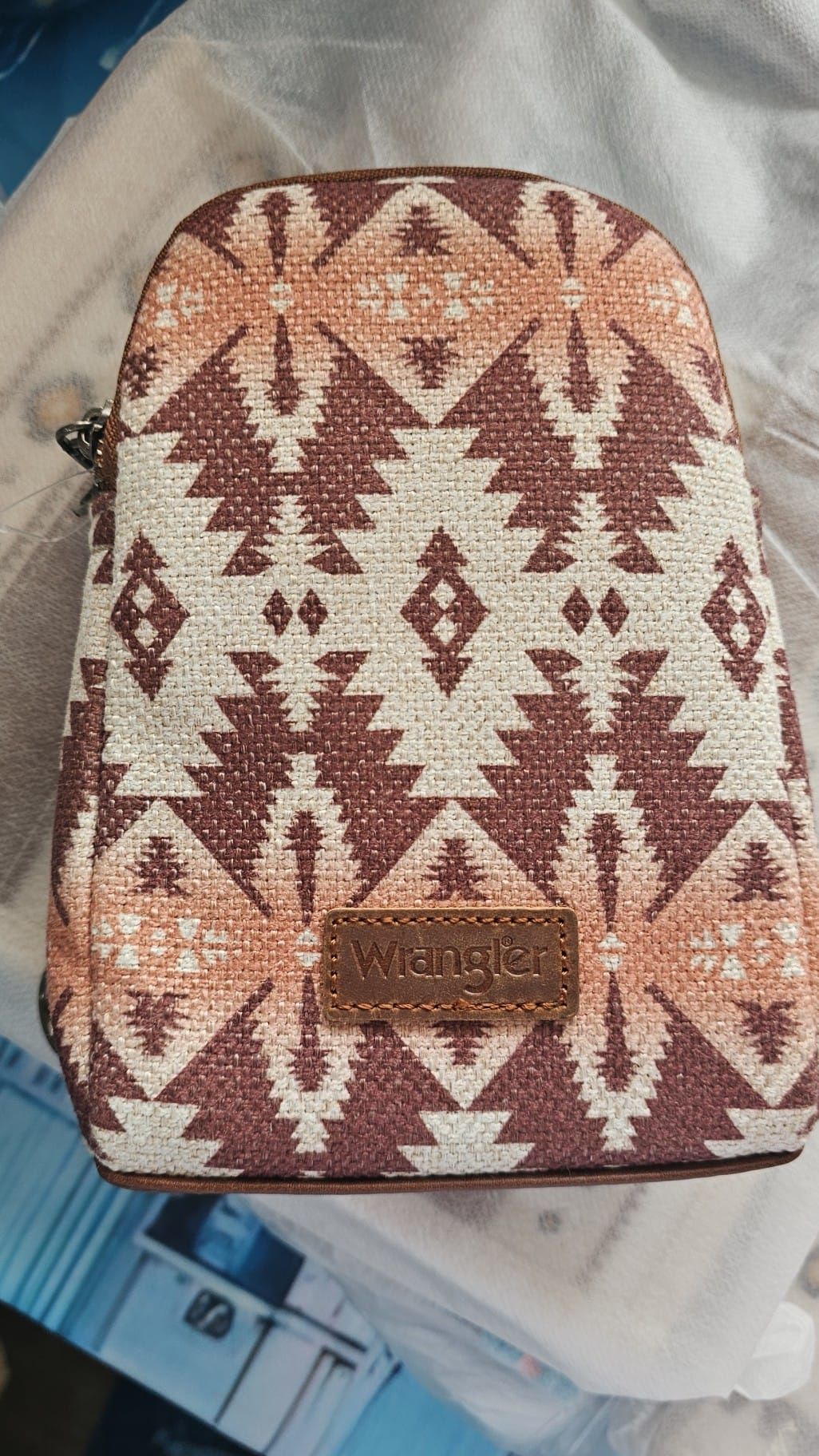 A brown and white backpack with a native american pattern is sitting on a table.