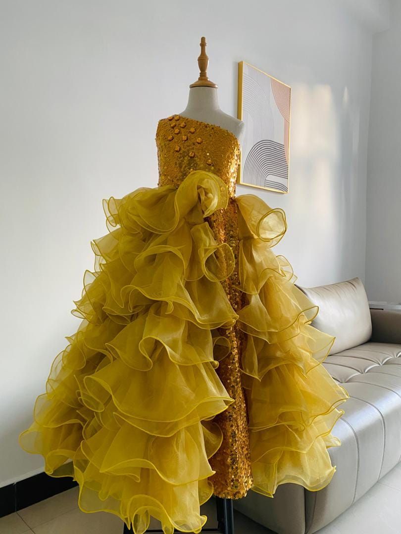 A yellow dress is on a mannequin in a living room next to a couch.