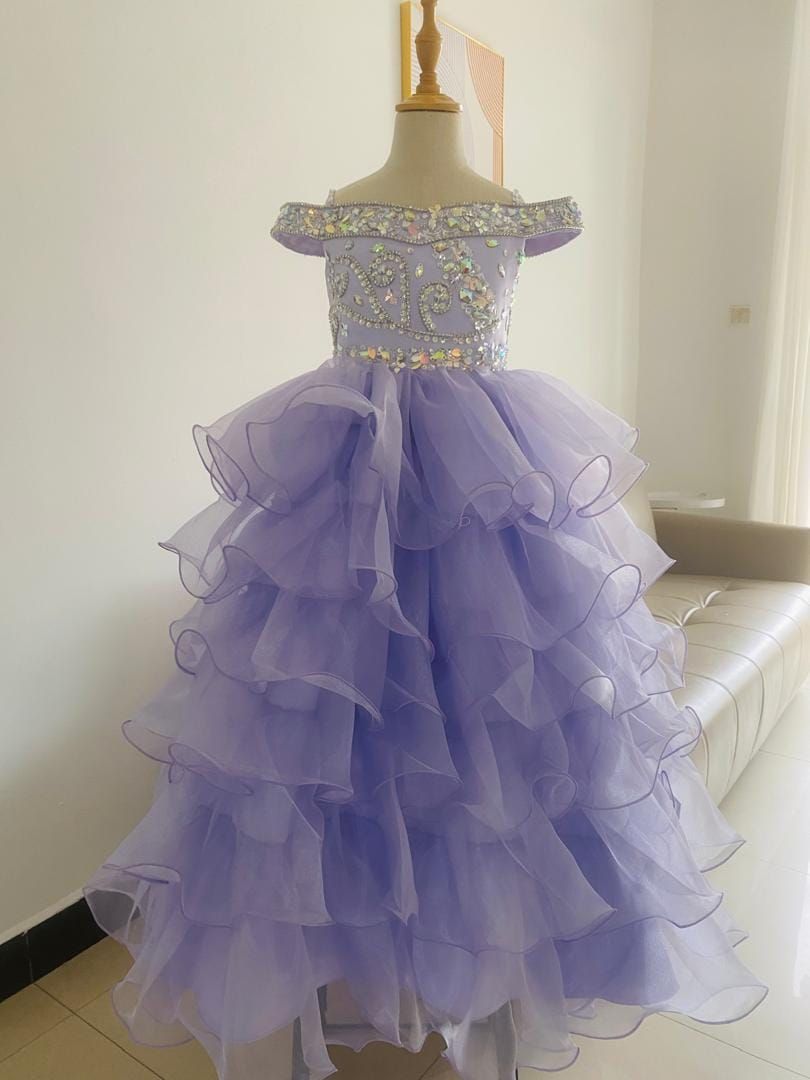 A purple dress is on a mannequin in a room.