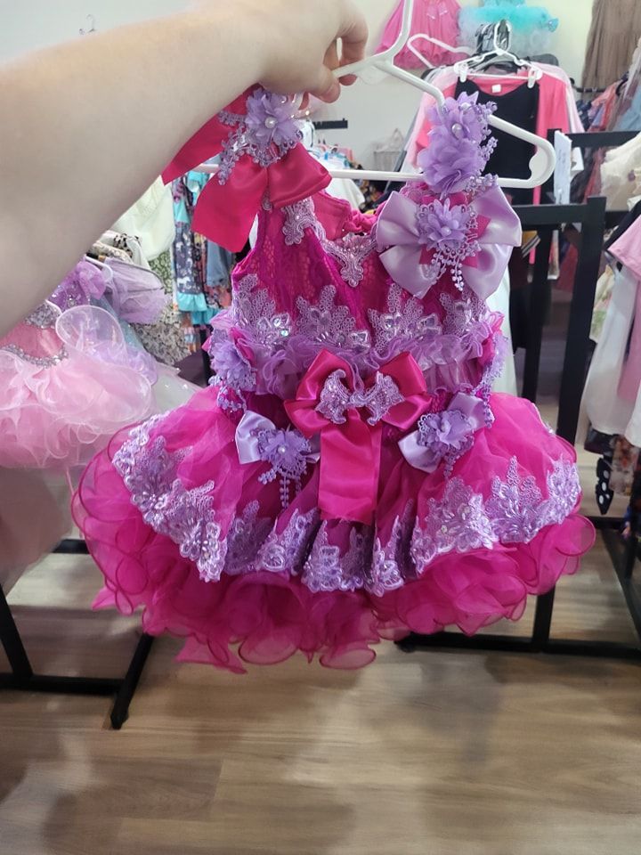 A person is holding a pink and purple dress in a store.