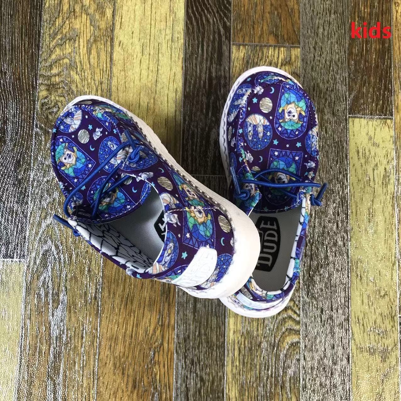 A pair of kids shoes are sitting on a wooden floor.